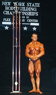 best selling author and bodybuilder tom venuto onstage with huge trophy